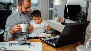 Father working from home with his son on his lap