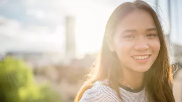 Young attractive millennial generation woman standing on the Pyrmont Bridge in Darling Harbour looking over with a bright smile. Darling Harbour. Downtown Sydney, New South Wales, Australia