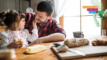 Toddler feeding bread to her father as they have breakfast