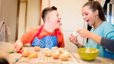 A boy with down syndrome bakes cakes with his sister in the kitchen.