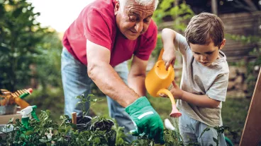 Grandfather and grandson playing in backyard with gardening tools Grandfather and grandson playing in backyard with gardening tools