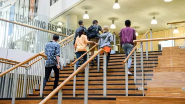 Male and female college students in casual clothing, on way to class, ascending staircase