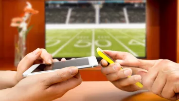 Friends using mobile phone and betting during a american football match Friends using mobile phone and betting during a american football match