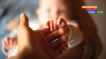 Close up of a hand holding newborn baby's hand