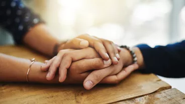 Cropped shot of two people holding hands in comfort