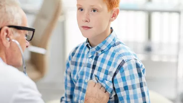 A teenage boy getting his heart checked by a doctor