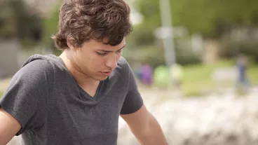 Young man sitting by himself and looking sad