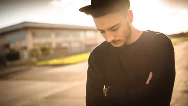 Young adult man looking pensive at dusk