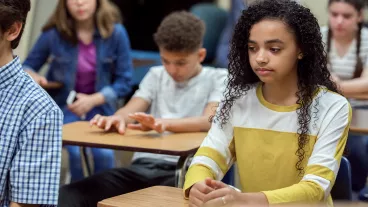 Teen girl sitting in a classroom looking pensive