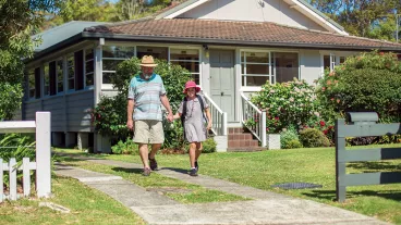 A school girl holding her grandfather's hand and walking down the path of the house