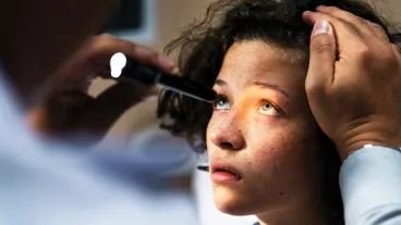 A youg girl having her eyes examined by a medical doctor