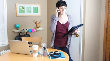 Young woman millennial working in home office telecommuting using laptop computer, mobile devices doing business function. 