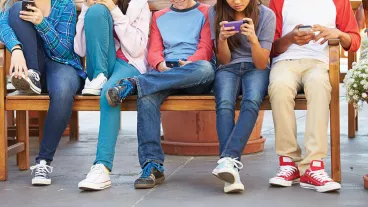 Group of youths playing with mobile devices.