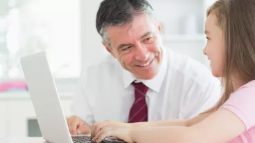 Man smiling at child using a laptop