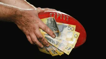 Hands holding football and money.
