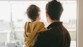 Rear view of dad holding his baby boy looking out of the window at home. Rear view of dad holding his baby boy looking out of the window at home.