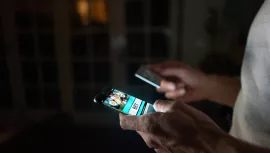 Close-up on a person betting online at home on their cell phone using their credit card.