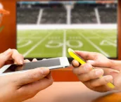 Friends using mobile phone and betting during a american football match