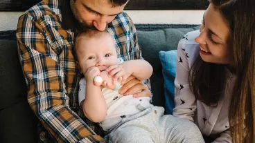 Portrait of young smiling family with son playing with toy. Happy family, parenthood and people concept - mother, father with baby at home.