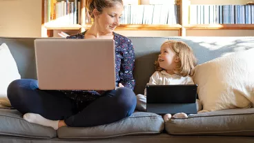 Mother working from home with daughter watching tablet Mother working from home with daughter watching tablet