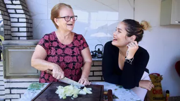 Happy mother and daughter talk while cooking in a rustic kitchen